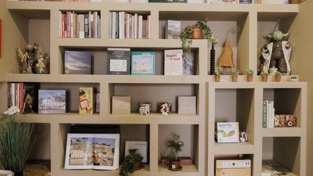 A bookshelf with various books, decorative items, and a Star Wars figurine.