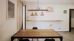 A dining area with a wooden table, black chairs, pendant lights, and artwork on the walls.