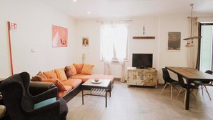 A living room with a sofa, coffee table, TV, and dining area.