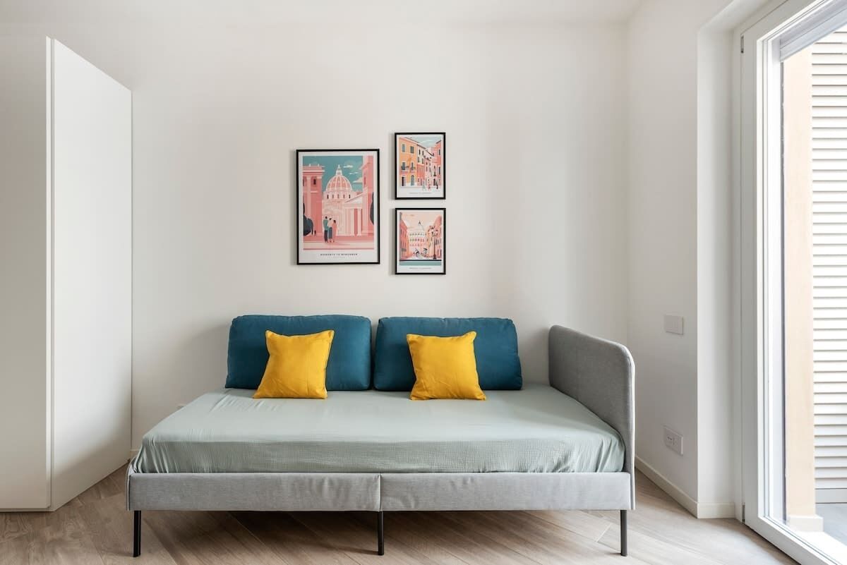 Una sala de estar moderna con un sofá gris, dos cojines amarillos y tres cuadros en la pared.