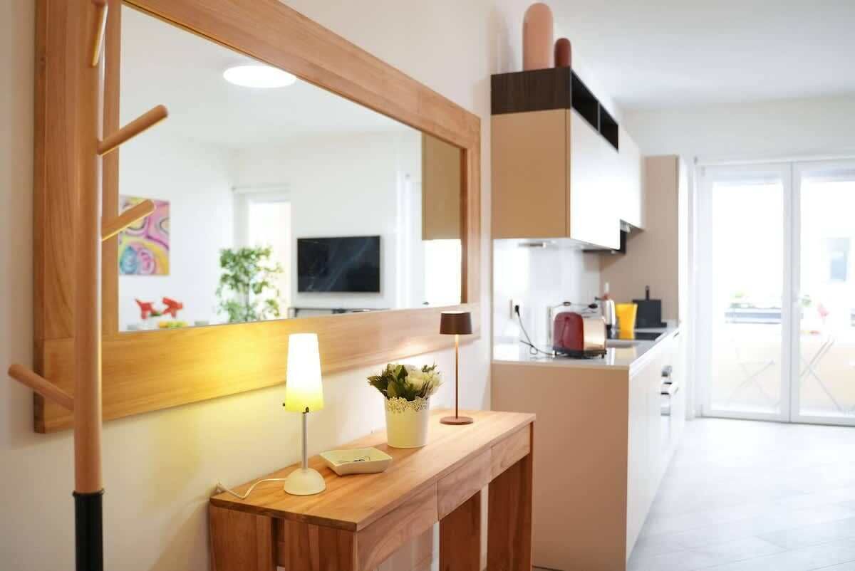 A modern kitchen with a wooden countertop, a large mirror, and a potted plant.