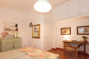Un dormitorio con cama, escritorio, silla y armario.