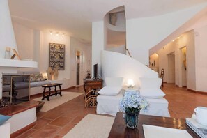 Una sala de estar moderna con un sofá blanco, una mesa de centro de madera y un jarrón decorativo.