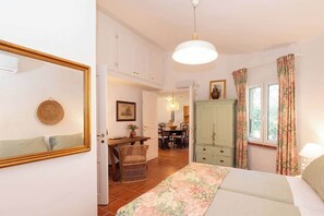 A bedroom with a bed, a wardrobe, a mirror, and a dining area in the background. - Villa Gioia | Tranquil Hideaway Beach Cottage (Pula)