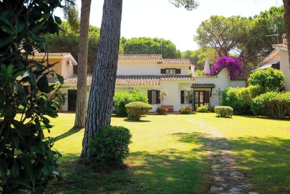 Una villa con techo de tejas, camino de piedra y jardines cuidados.