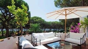 An outdoor seating area with a white sofa, a glass coffee table, and a large umbrella. - Villa Gioia | Tranquil Hideaway Beach Cottage (Pula)