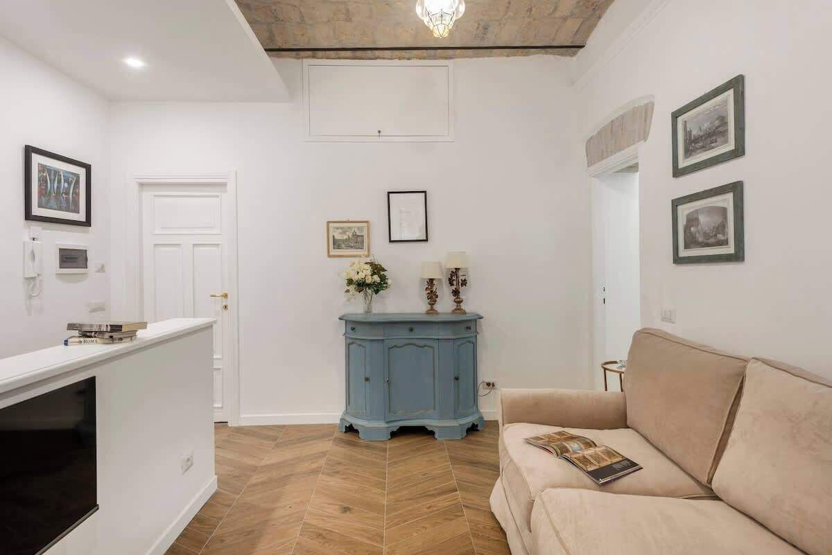 Ein Zimmer mit einem beigefarbenen Sofa, einem blauen Schrank und gerahmten Bildern an der Wand.