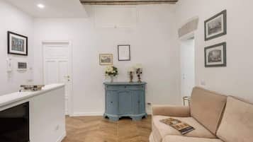 Ein Zimmer mit einem beigefarbenen Sofa, einem blauen Schrank und gerahmten Bildern an der Wand.