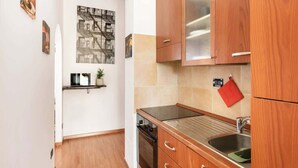 Een kleine keuken met houten kastjes, een roestvrijstalen spoelbak en een klein aanrecht.