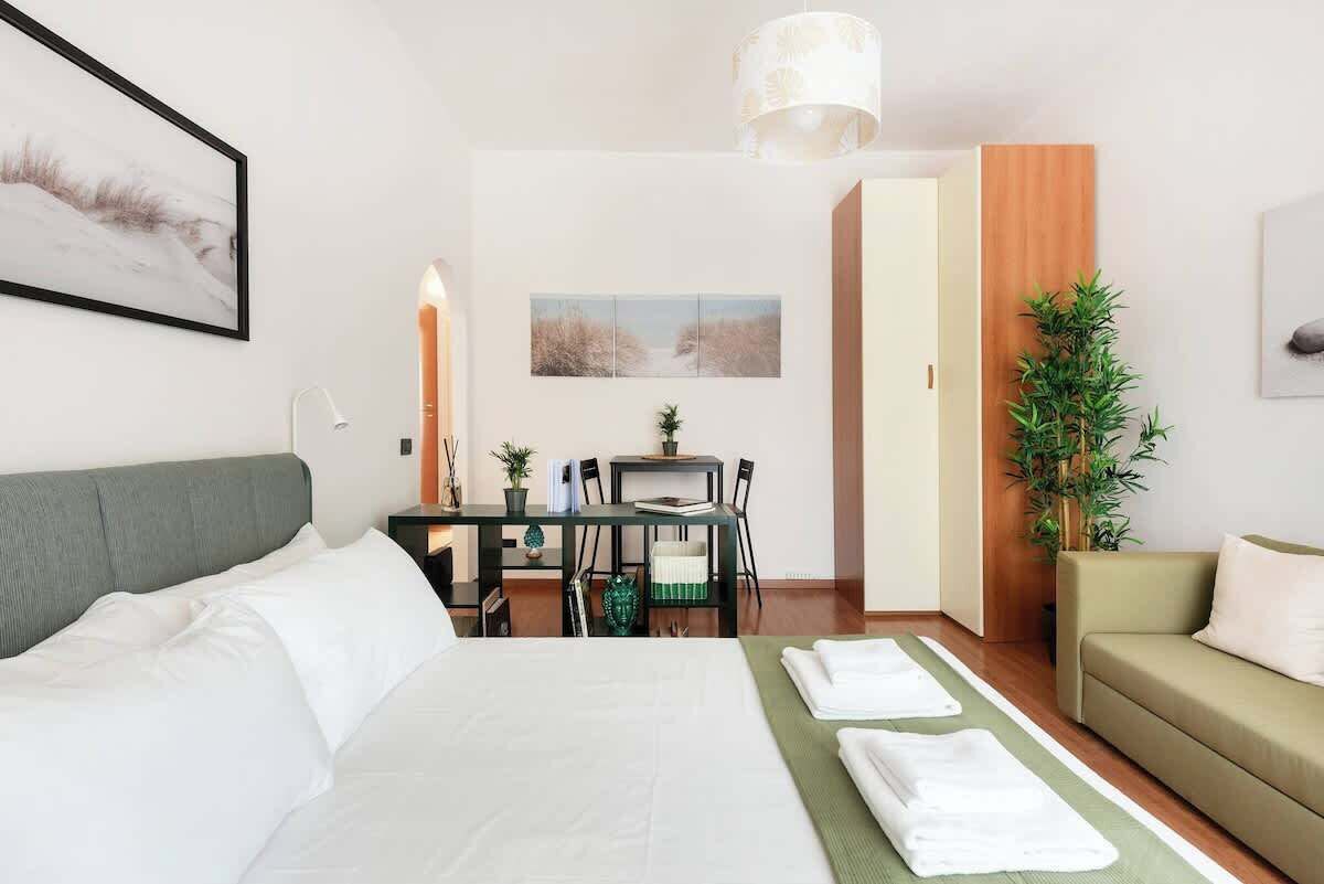 Ein Hotelzimmer mit einem Bett, einem Schreibtisch, einem Stuhl, einem Tisch, einer Couch und einer Topfpflanze.