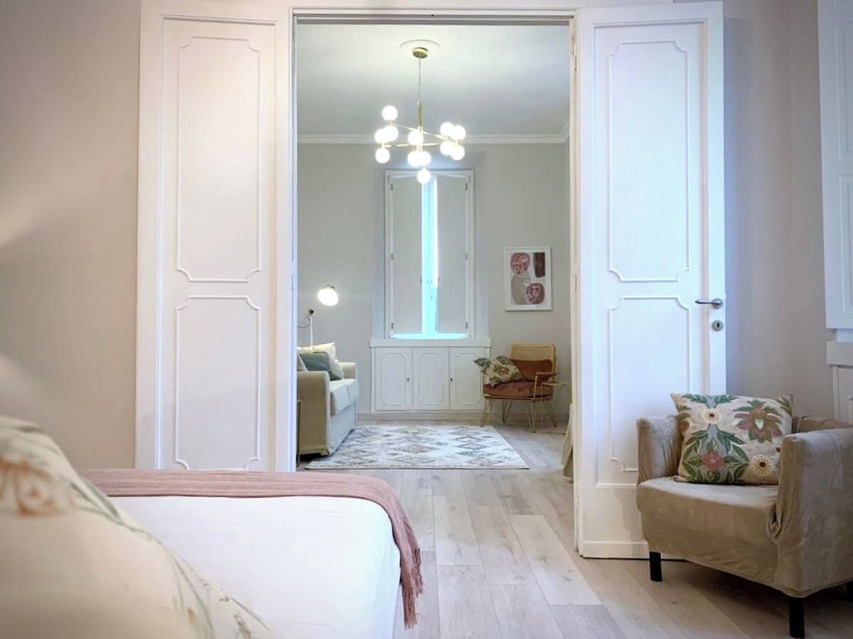 A bedroom with a bed, a chair, a desk, and a window.