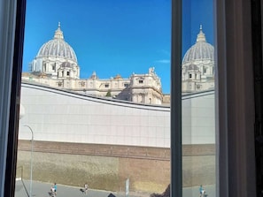 Vista de um edifício grande com uma cúpula imponente e uma parede em primeiro plano.