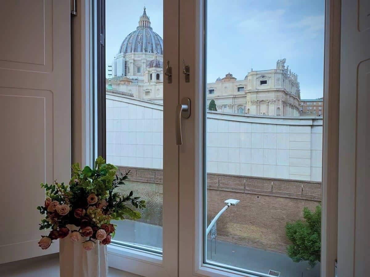 A window with a view of a historic building with domes and classical architecture.