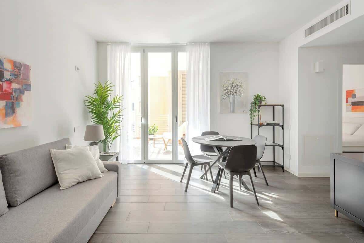 A modern living room with a sofa, dining table, chairs, and a TV.