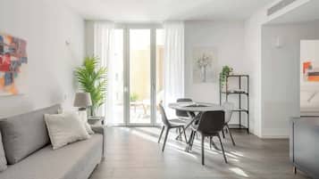 A modern living room with a sofa, dining table, chairs, and a TV.