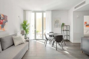 Ein modernes Wohnzimmer mit einer Couch, einem Esstisch, Stühlen und einem Fernseher.