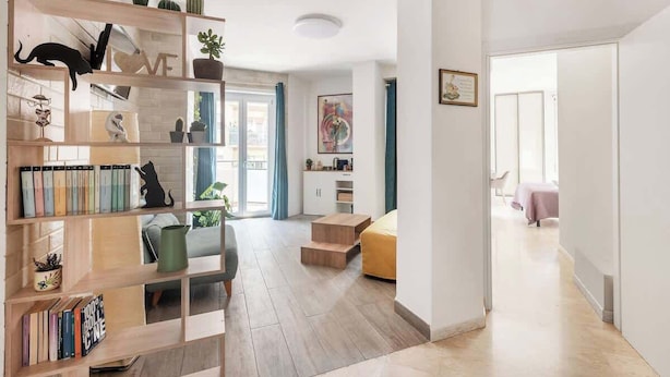 A modern living room with a wooden bookshelf, a sofa, and a dining area. - Aria di Trastevere | Double Bedroom "2" en suite (Rome)