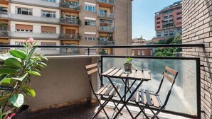 A balcony with a table and chairs, a potted plant, and a view of a building with balconies. - Aria di Trastevere | Double Bedroom "2" en suite (Rome)