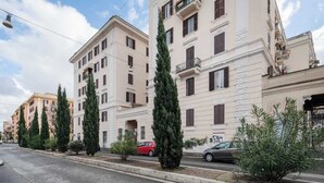 A street with multi-story buildings, parked cars, and a sidewalk with trees. - Classy and Chic San Lorenzo | 2BR | Kitchen (Rome)