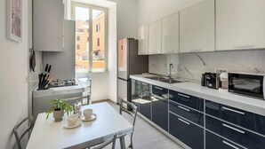 A modern kitchen with a dining area, a window, and a view of buildings outside.