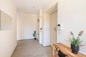 Un couloir avec un banc en bois, des plantes en pot et une porte donnant sur une autre pièce.