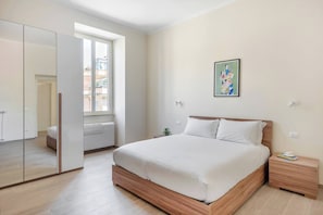 Quarto com cama grande, guarda-roupa, mesa de cabeceira e janela.