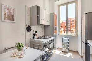 Cozinha moderna com fogão embutido, forno e armários. Uma janela oferece vista para edifícios.