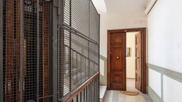 Un couloir avec une rambarde en métal, une porte en bois et un tapis à motifs.