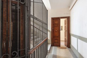Un couloir avec une rambarde en métal, une porte en bois et un tapis à motifs.