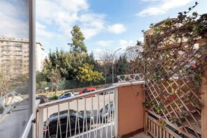 Un balcon donnant sur une rangée de voitures garées et un immeuble en arrière-plan.