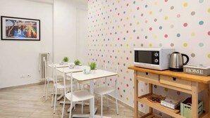A dining area with a white table and chairs, a microwave on a wooden shelf, and a polka dot wall. - Street Art Roma | 3BR apartment | Near Tiburtina (Rome)