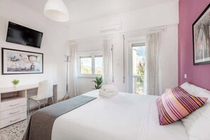 A hotel room with a bed, a desk, a chair, a TV, and a window with curtains. - Street Art Roma | 3BR apartment | Near Tiburtina (Rome)