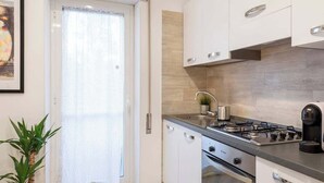 A modern kitchen with white cabinets, a gas stove, and a coffee maker. - Street Art Roma | 3BR apartment | Near Tiburtina (Rome)