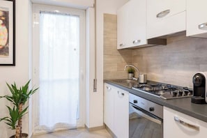 A modern kitchen with white cabinets, a gas stove, and a coffee maker. - Street Art Roma | 3BR apartment | Near Tiburtina (Rome)