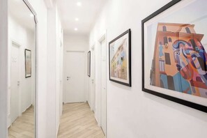 A hallway with framed artworks on the walls and a door at the end. - Street Art Roma | 3BR apartment | Near Tiburtina (Rome)