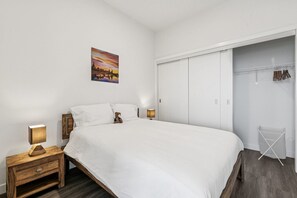 Un dormitorio con cama, mesitas de noche, armario y una lámpara colgante, además de un cuadro en la pared.