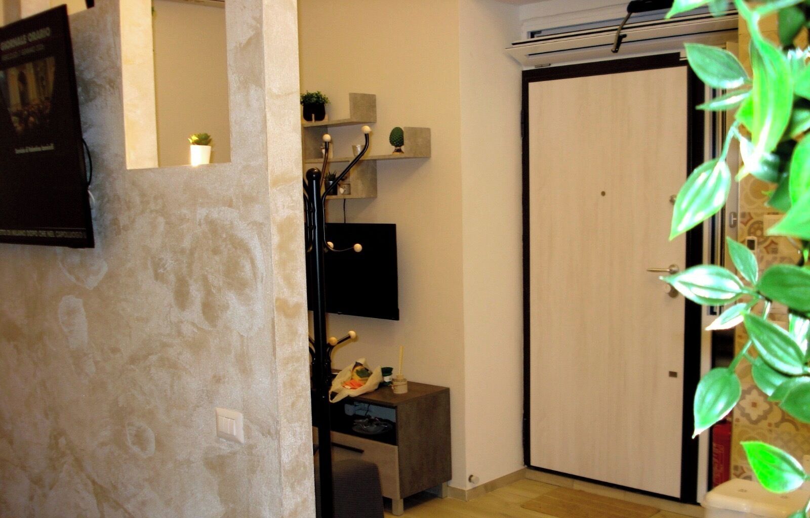 A room with a stone wall, a flat-screen TV mounted on the wall, a small table with a guitar, and a sliding door.