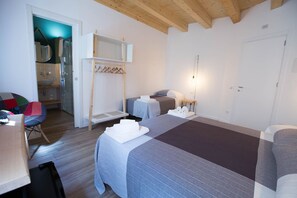 Ein Hotelzimmer mit zwei Betten, einer Holzbalkendecke, einem kleinen Tisch und einem Sessel.