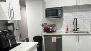 Una cucina moderna con mobili bianchi, un piano cottura in acciaio inossidabile, un forno a microonde e una lavastoviglie.