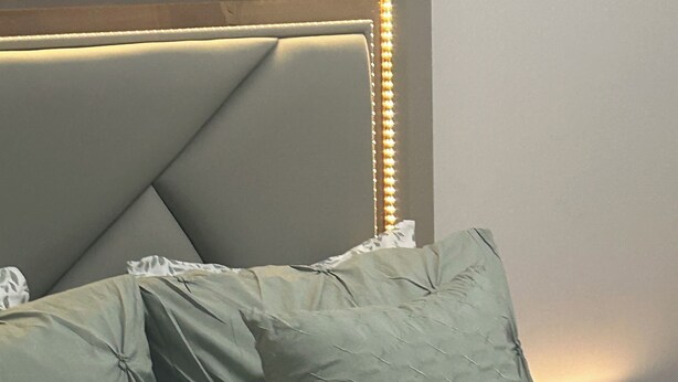 Un letto con testiera, cuscini e coperta.