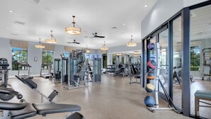 A gym with exercise equipment, large windows, and ceiling fans. - Nine Bedroom Vacation Home ChampionsGate (Davenport)
