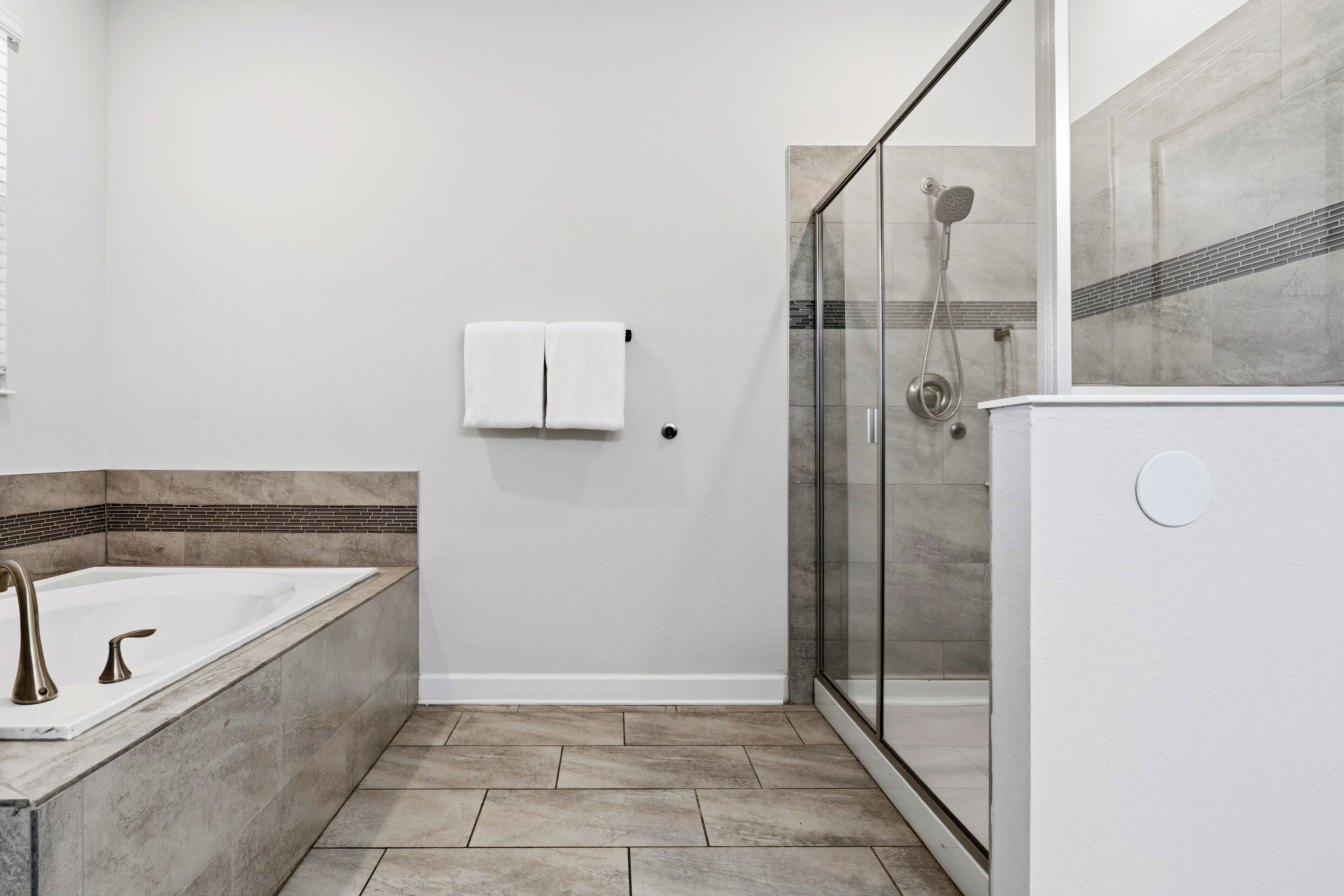 A modern bathroom with a glass-enclosed shower, a bathtub, and a towel rack.