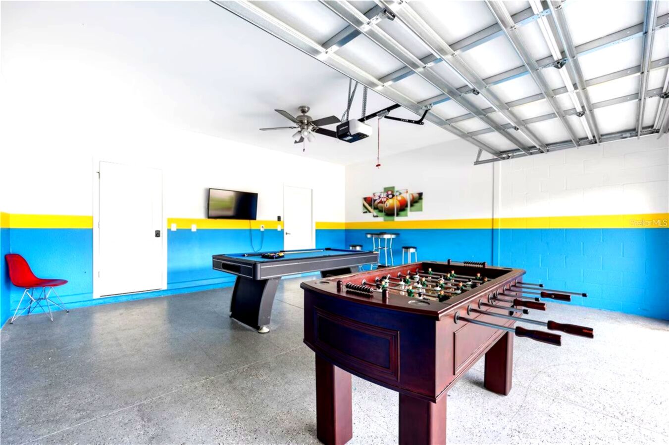 Ein Zimmer mit Poolbillard, Kicker und einem an der Wand befestigten Fernseher.