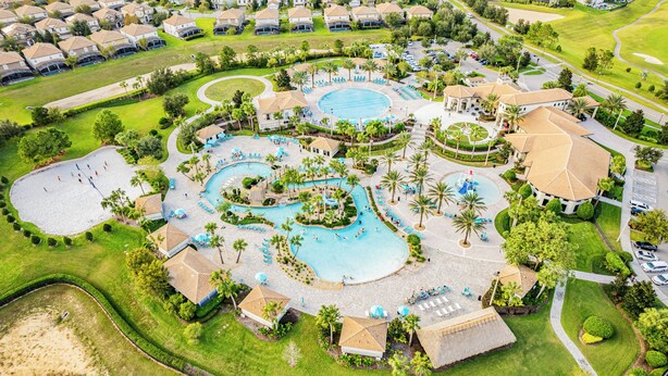 An aerial view of a resort with multiple swimming pools, palm trees, and a golf course. - Nine Bedroom Vacation Home ChampionsGate (Davenport)