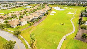 A golf course with a clubhouse, sand bunkers, and a pond. - Nine Bedroom Vacation Home ChampionsGate (Davenport)