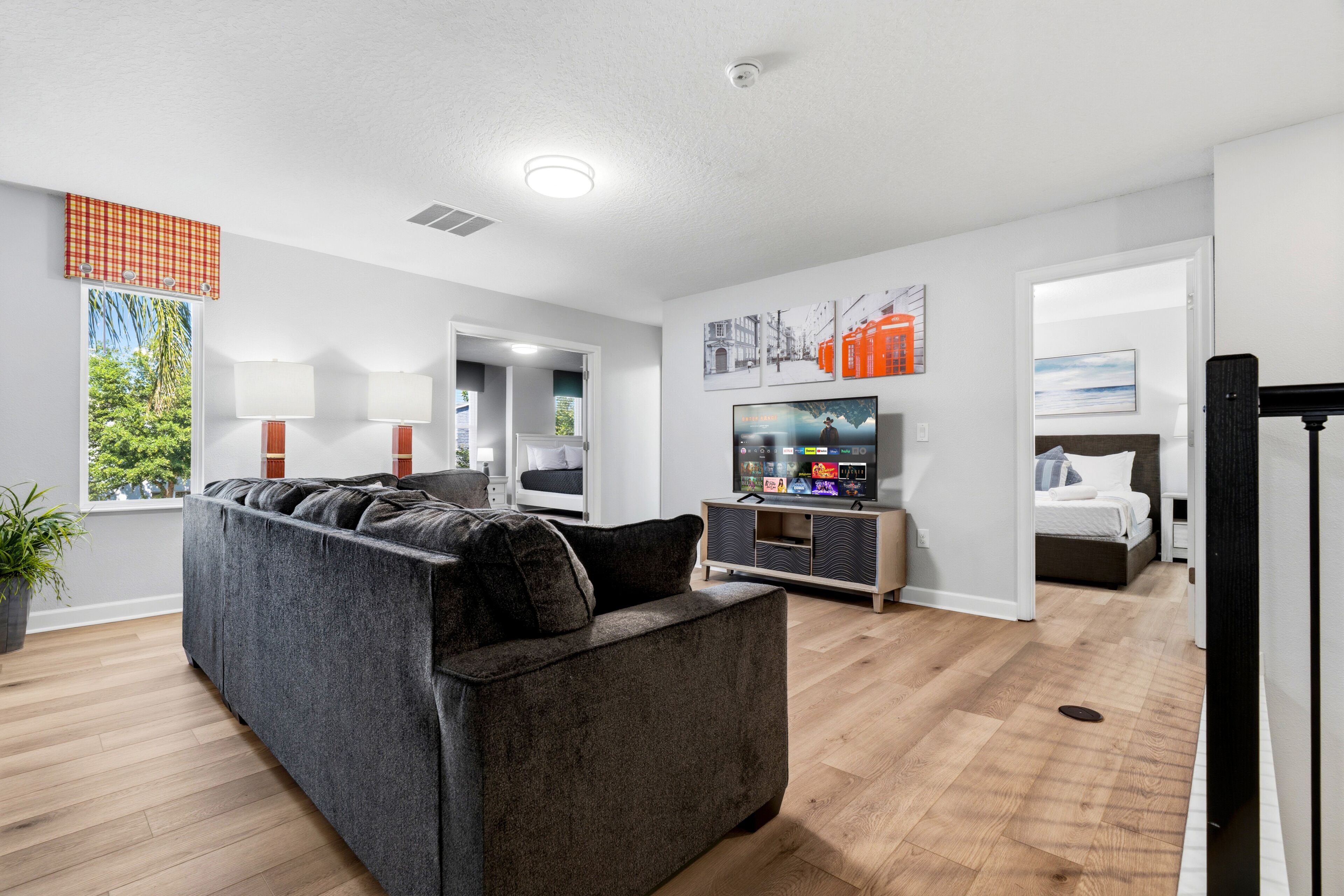 Ein modernes Wohnzimmer mit einem Ecksofa, einem Flachbildfernseher und einem Essbereich mit Tisch und Stühlen.