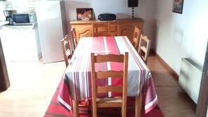 A dining area with a table set for six, wooden chairs, a red and white tablecloth, and a kitchen in the background. - Independent apartment for rent in a villa on the 1st floor in Saint Jean de Luz. (Saint-Jean-de-Luz)