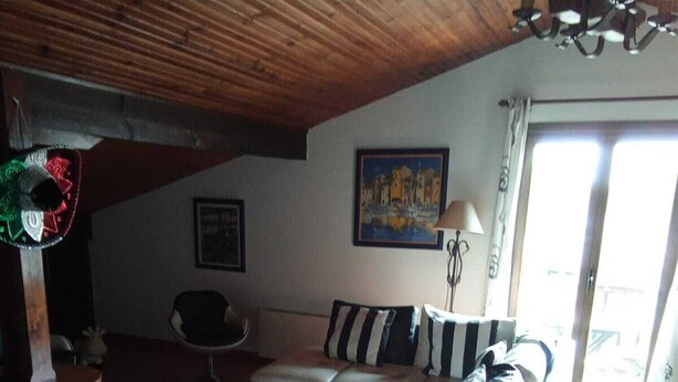 A living room with a wooden ceiling, a black and white sofa, a white coffee table, and a painting on the wall. - Independent apartment for rent in a villa on the 1st floor in Saint Jean de Luz. (Saint-Jean-de-Luz)