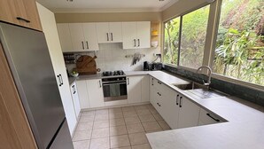 A modern kitchen with white cabinets, a stainless steel refrigerator, and a window with a view of greenery. - Cowan Lodge Cowan Cowan (Cowan Cowan)