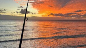A fishing rod held over a beach with a sunset in the background. - Cowan Lodge Cowan Cowan (Cowan Cowan)